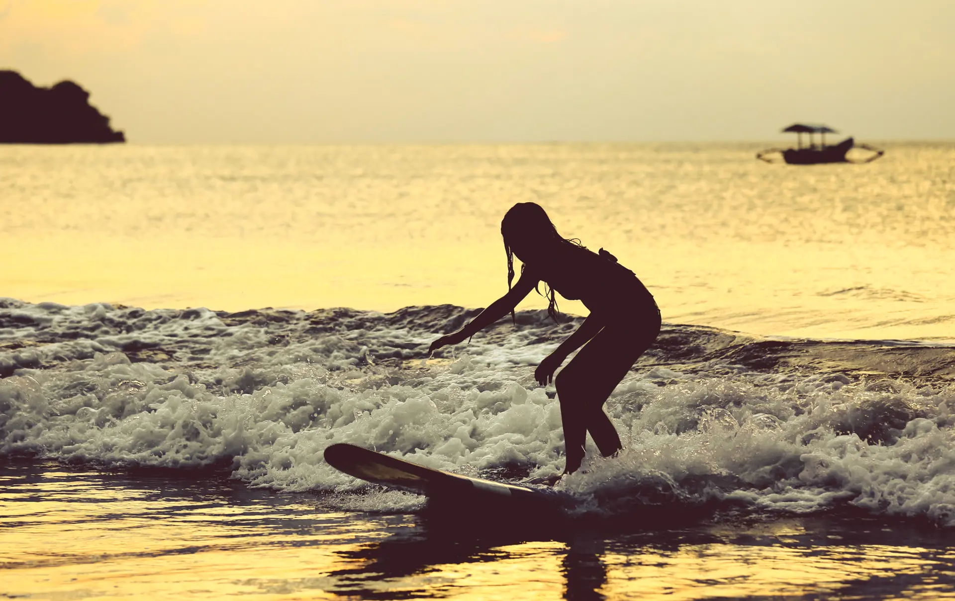 shutterstock_492020038 Silhouette of surfer girl surfing on her board on the tropical Jimbaran beach..jpg