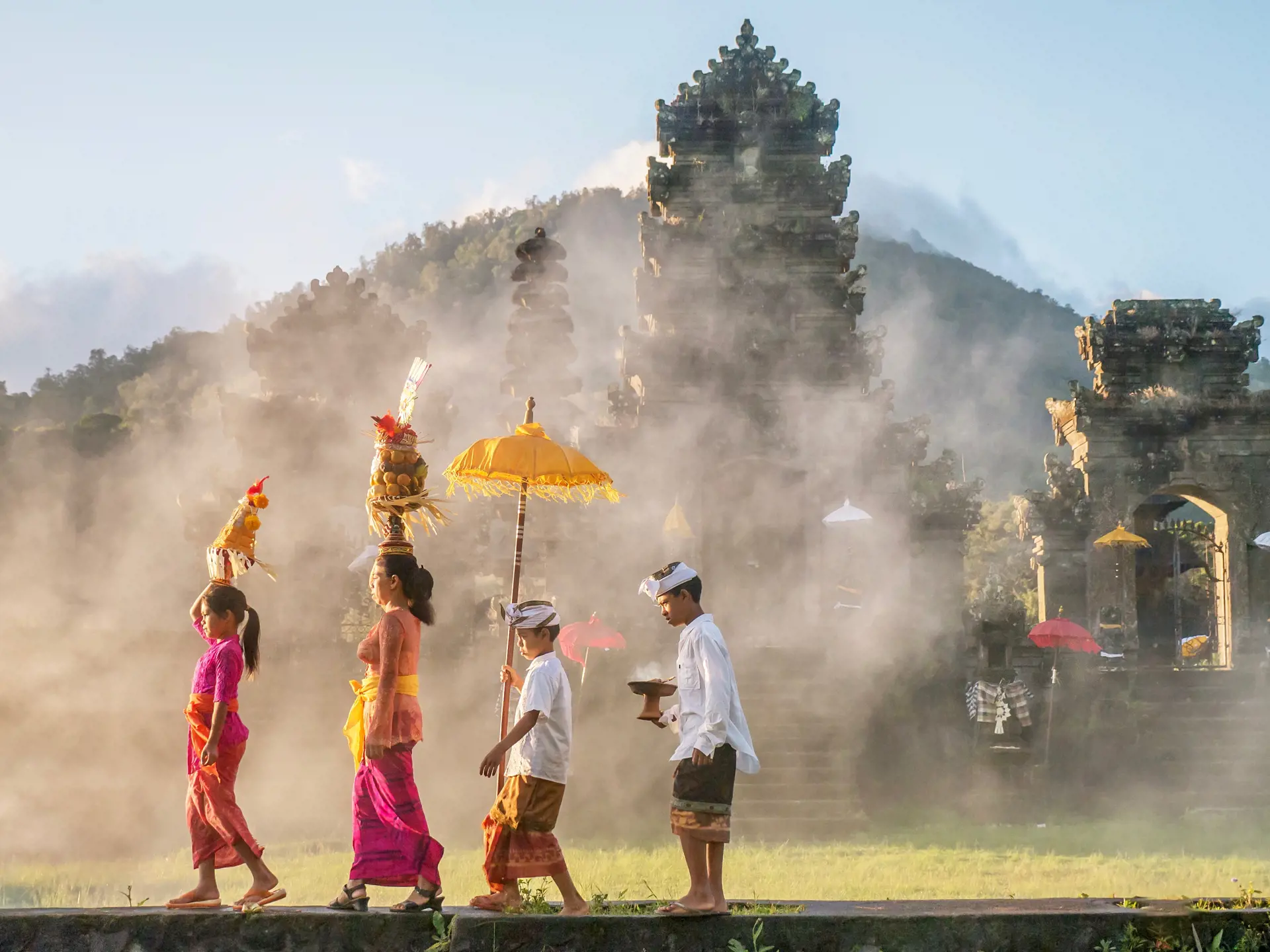 shutterstock_1053593438 Ubud, Bali - July 30, 2016. Illustrative Editorial. Showing traditional Balinese male and female ceremonial clothing and religious offerings, as a mother and children walk to a Hindu.jpg