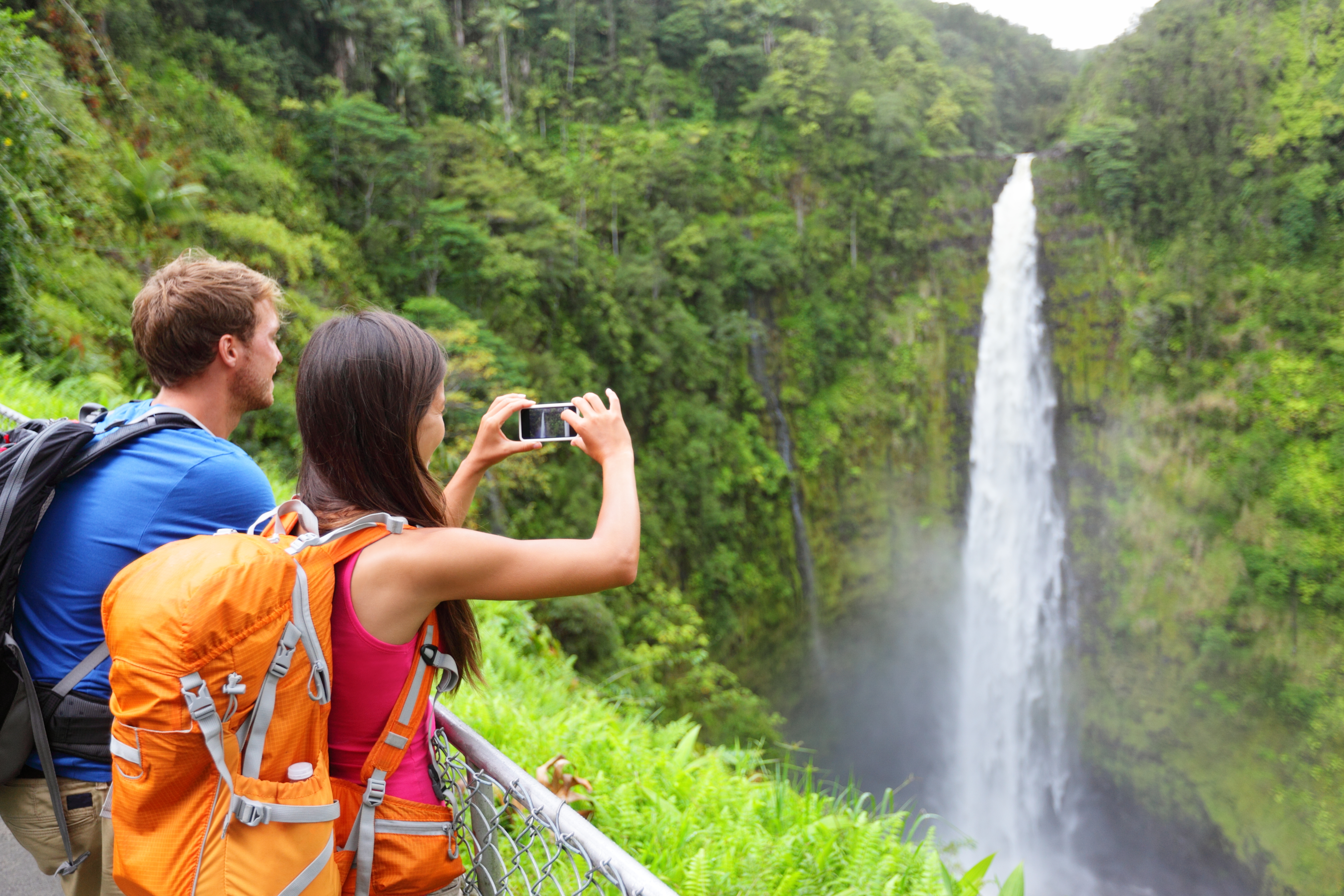 Couple tourists on Hawaii by waterfall. Tourist taking photo pictures of Akaka Falls waterfall on Hawaii, Big Island.jpg