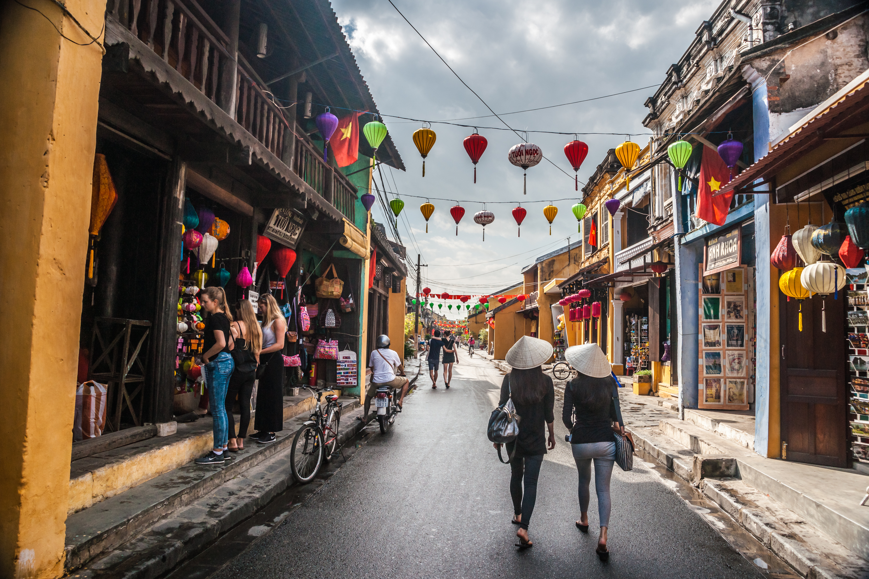 HOI AN, VIET NAM Two unidentified asian female tourists in traditional vietnamese conical hats walk.jpg