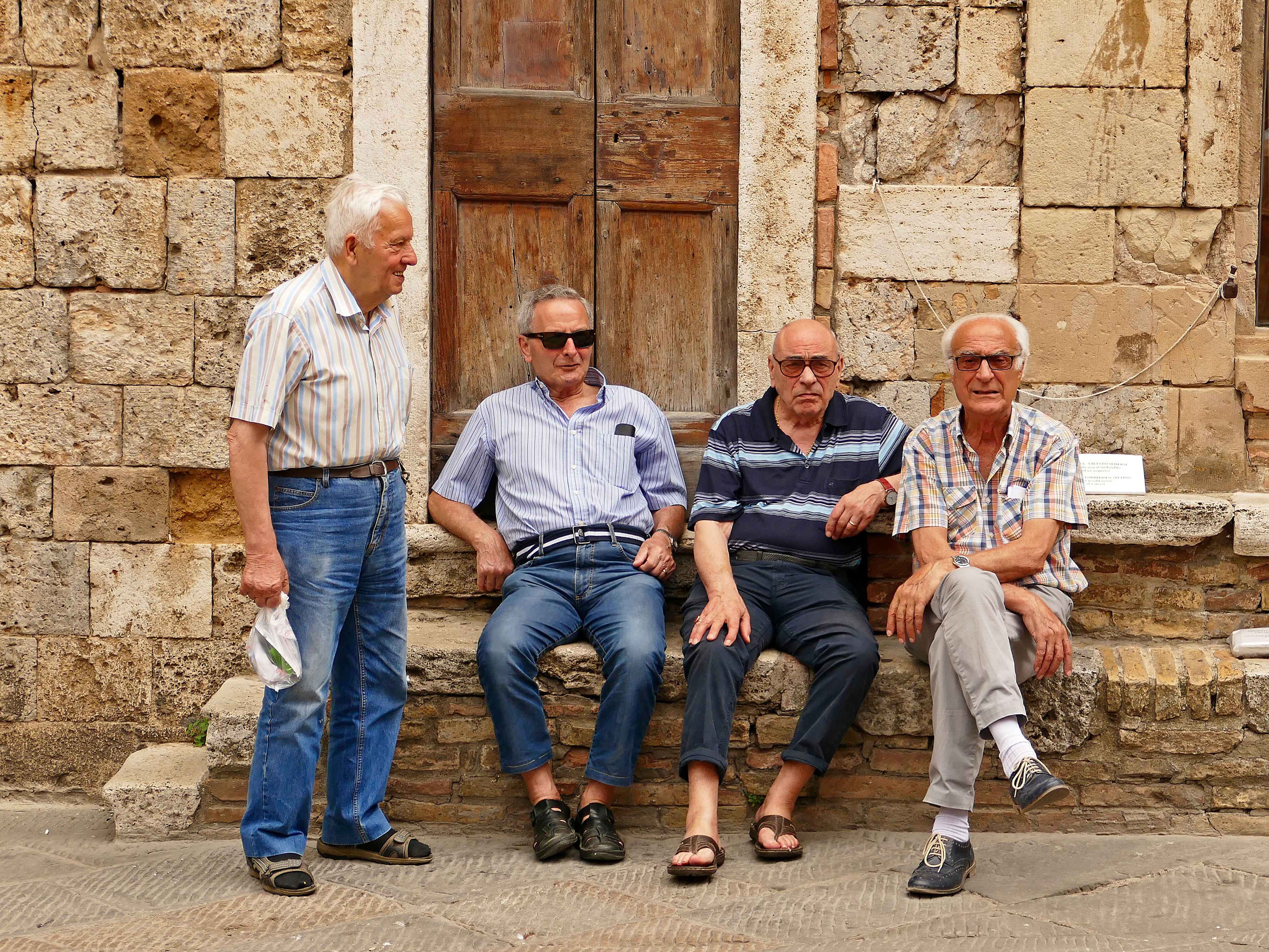Gamla vänner pratar på ett torg i San Gimignano