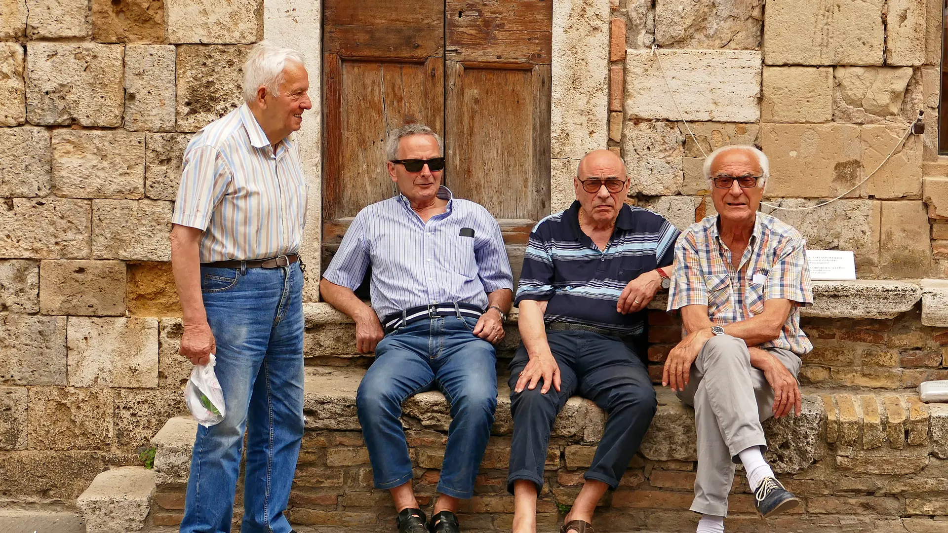 Gamla vänner pratar på ett torg i San Gimignano
