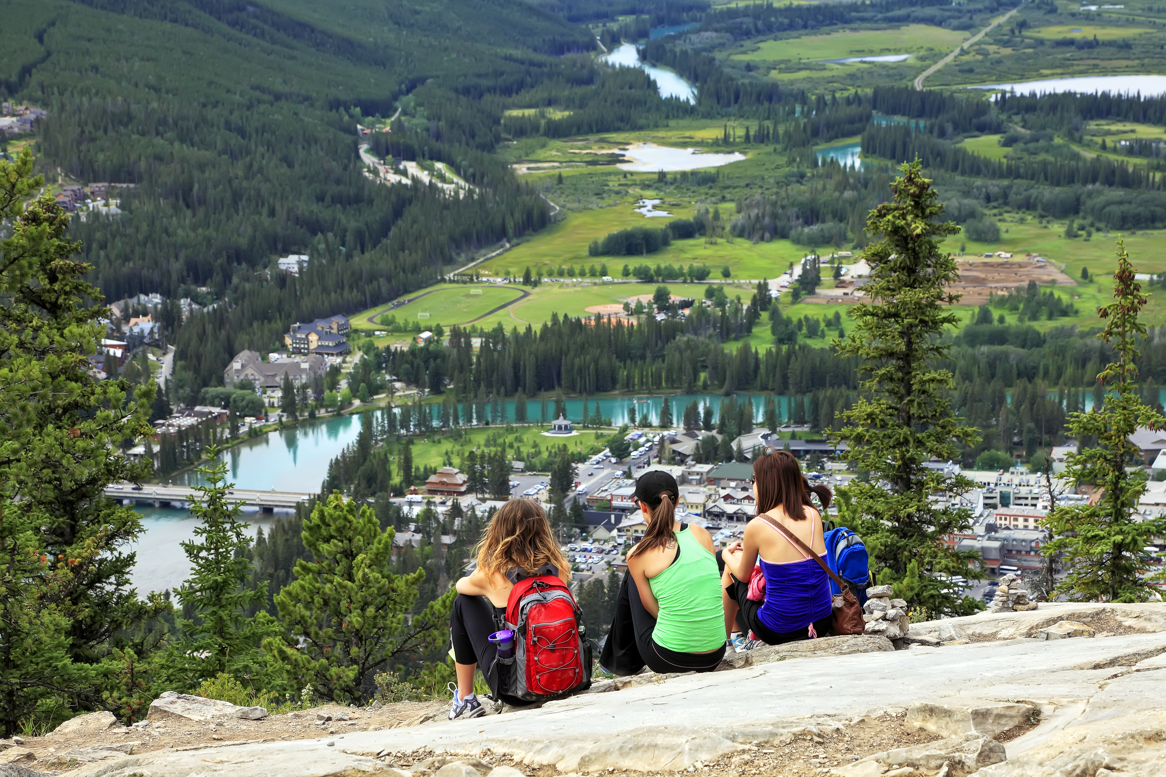 shutterstock_83229271 ourists sitting on a grief and looking at a panorama of a small town Banff in a Bow river valley (Banff NP).jpg